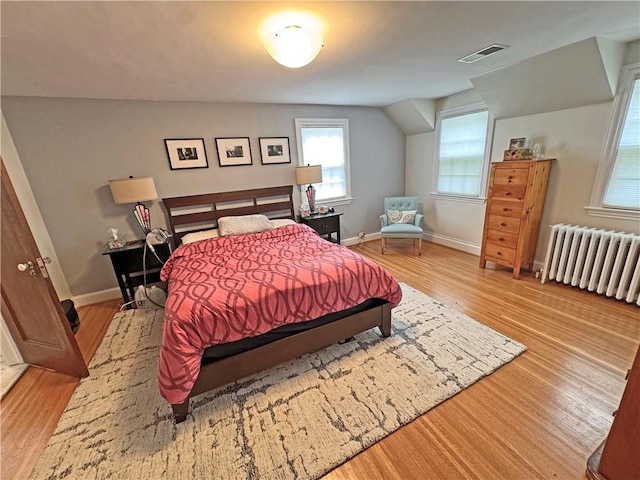 290 Hollywood Ave, Brighton, NY 14618 - bedroom featuring wood finished floors, radiator heating unit, multiple windows, and vaulted ceiling