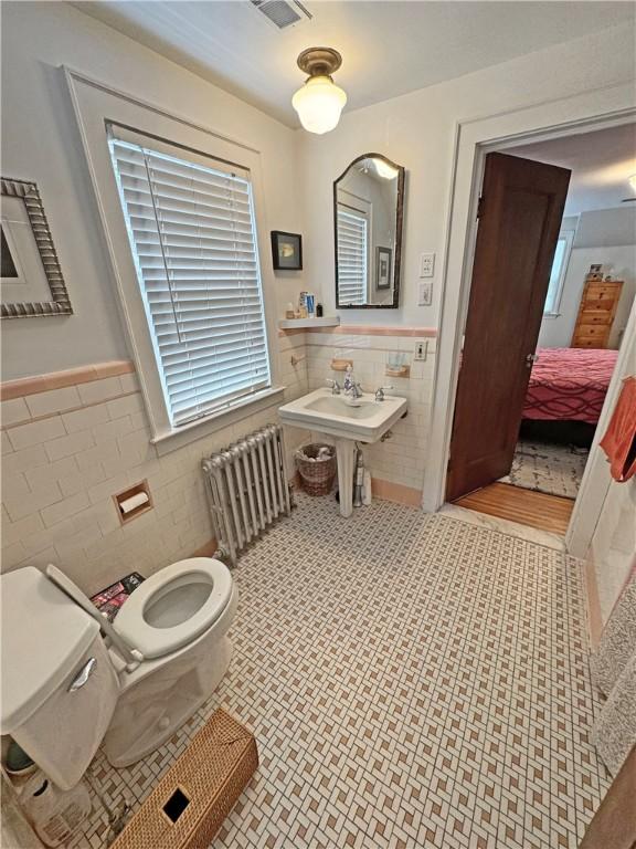 290 Hollywood Ave, Brighton, NY 14618 - bathroom featuring tile walls, radiator heating unit, wainscoting, tile patterned floors, and ensuite bathroom