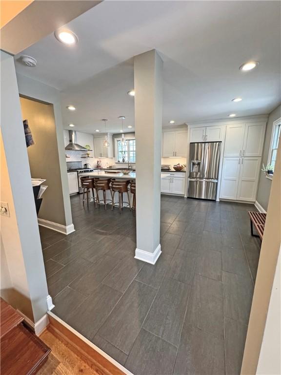 290 Hollywood Ave, Brighton, NY 14618 - kitchen featuring stainless steel appliances, wall chimney exhaust hood, white cabinetry, a kitchen bar, and recessed lighting
