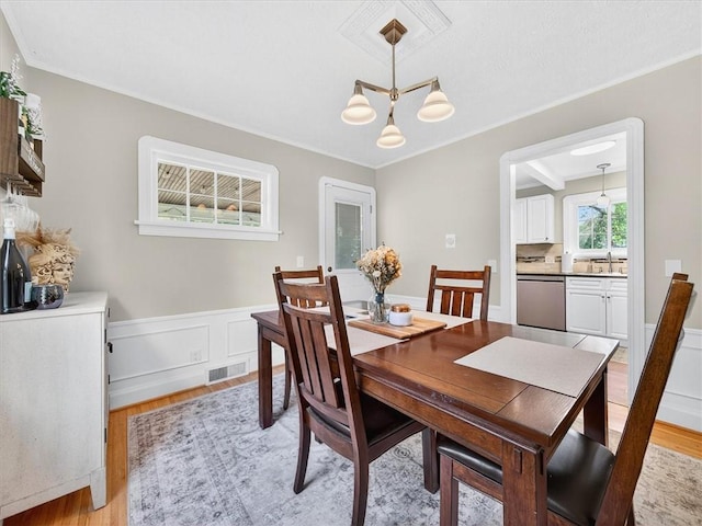 245 Worthington Rd, Irondequoit, NY 14622 - dining space with light wood-style flooring, a chandelier, ornamental molding, and a wainscoted wall