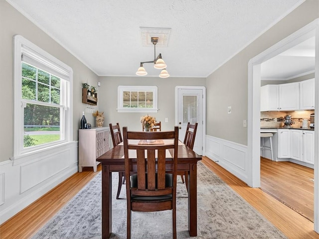 245 Worthington Rd, Irondequoit, NY 14622 - dining room with crown molding, light wood-type flooring, a chandelier, wainscoting, and a decorative wall
