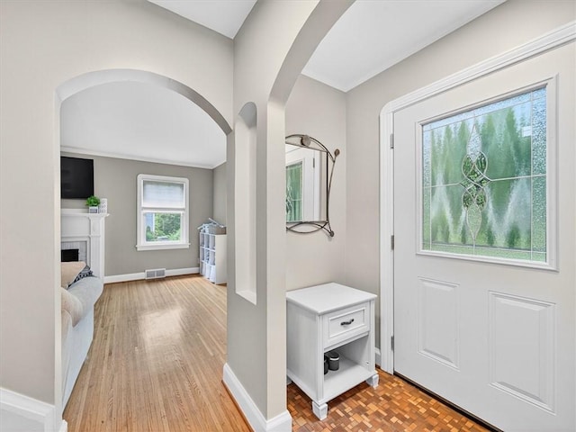 245 Worthington Rd, Irondequoit, NY 14622 - foyer featuring arched walkways, light wood-style flooring, and a brick fireplace