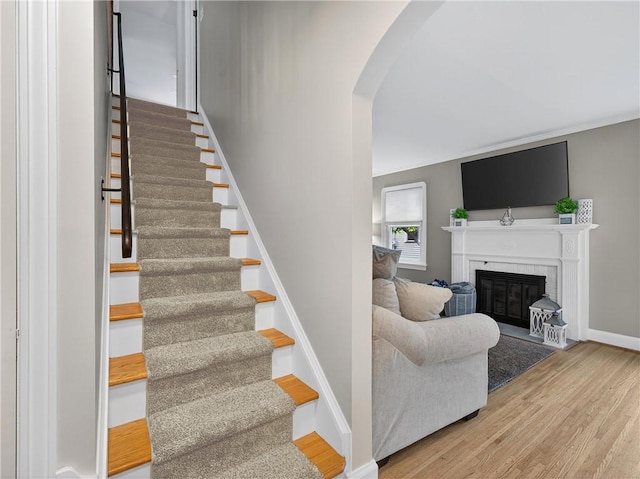 245 Worthington Rd, Irondequoit, NY 14622 - stairs with wood finished floors, arched walkways, a glass covered fireplace, and crown molding