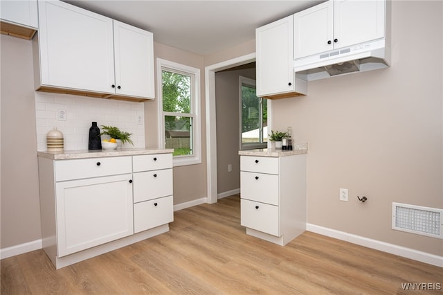 827 Tifft St, Buffalo, NY 14220 - kitchen featuring under cabinet range hood, decorative backsplash, light wood finished floors, and white cabinets