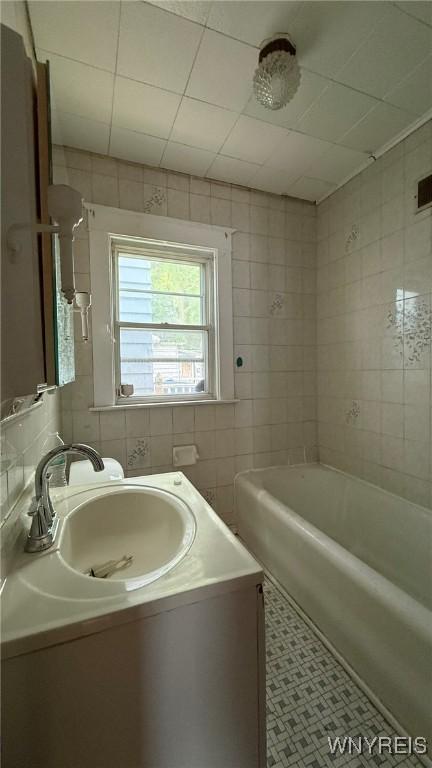 1890 Linwood Ave, Niagara Falls, NY 14305 - bathroom with tile walls, vanity, a bathtub, and tile patterned floors