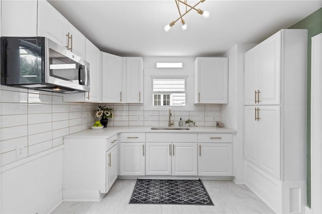 2079 Clifford Ave, Rochester, NY 14609 - kitchen with stainless steel microwave, light countertops, white cabinetry, and backsplash