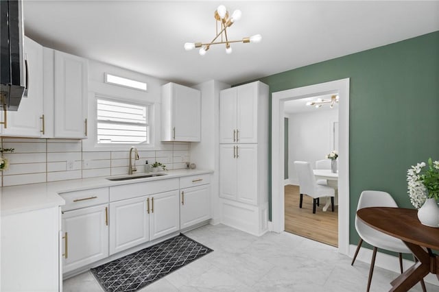2079 Clifford Ave, Rochester, NY 14609 - kitchen featuring a chandelier, backsplash, white cabinets, and light countertops