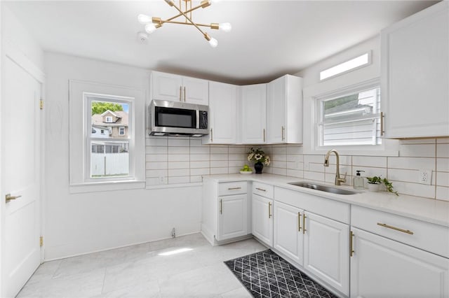 2079 Clifford Ave, Rochester, NY 14609 - kitchen featuring stainless steel microwave, backsplash, white cabinets, and light countertops