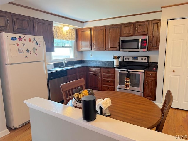 8467 Torchwood Ln, Cicero, NY 13039 - kitchen featuring stainless steel appliances, crown molding, light wood finished floors, and dark countertops