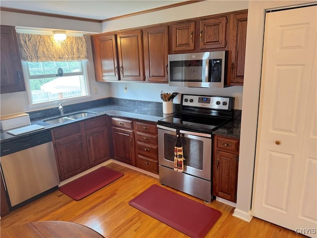 8467 Torchwood Ln, Cicero, NY 13039 - kitchen with stainless steel appliances, dark countertops, light wood finished floors, crown molding, and brown cabinets