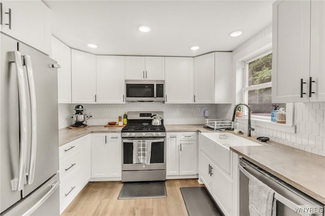 7052 Waring Cir, Evans, NY 14047 - kitchen featuring stainless steel appliances, light wood-type flooring, backsplash, white cabinetry, and recessed lighting