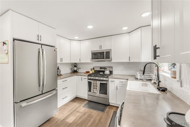 7052 Waring Cir, Evans, NY 14047 - kitchen with appliances with stainless steel finishes, light countertops, decorative backsplash, white cabinetry, and light wood-style floors