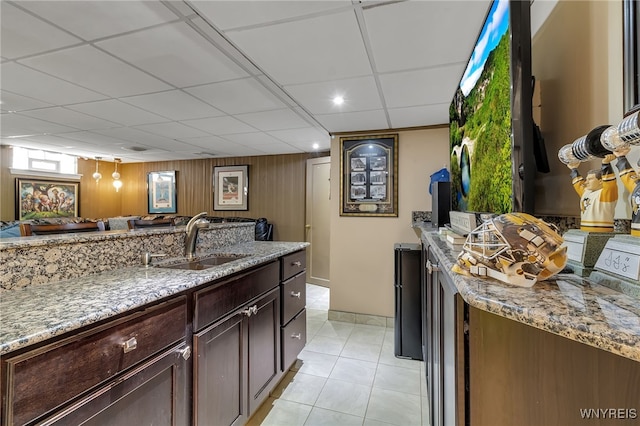 66 Devonshire Rd, Tonawanda, NY 14223 - kitchen with a paneled ceiling, light stone counters, light tile patterned floors, wood walls, and dark brown cabinets
