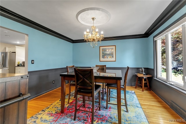 66 Devonshire Rd, Tonawanda, NY 14223 - dining room featuring crown molding, healthy amount of natural light, a chandelier, light wood-style flooring, and a wainscoted wall