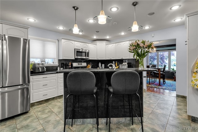 66 Devonshire Rd, Tonawanda, NY 14223 - kitchen featuring stainless steel appliances, dark countertops, a kitchen bar, white cabinets, and decorative backsplash