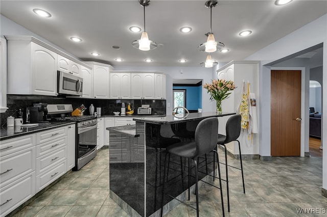 66 Devonshire Rd, Tonawanda, NY 14223 - kitchen with stainless steel appliances, a breakfast bar area, white cabinets, decorative backsplash, and pendant lighting