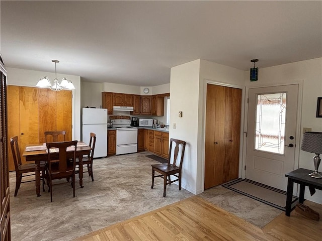 1237 County Highway 11, Davenport, NY 13860 - kitchen featuring white appliances, a chandelier, under cabinet range hood, hanging light fixtures, and brown cabinets