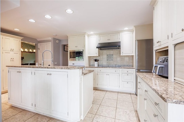 25 Killdeer Ln, Perinton, NY 14450 - kitchen featuring under cabinet range hood, appliances with stainless steel finishes, backsplash, light tile patterned floors, and a center island with sink