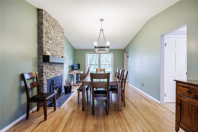 25 Killdeer Ln, Perinton, NY 14450 - dining space featuring vaulted ceiling, light wood-style flooring, a chandelier, and a fireplace
