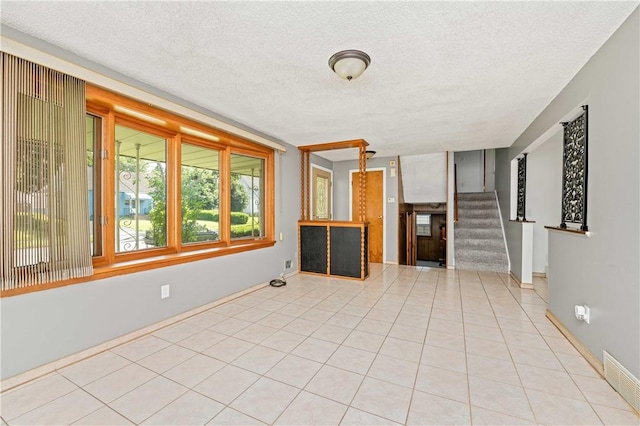 24 Gray St, Rochester, NY 14609 - unfurnished living room featuring a textured ceiling, stairway, and tile patterned flooring