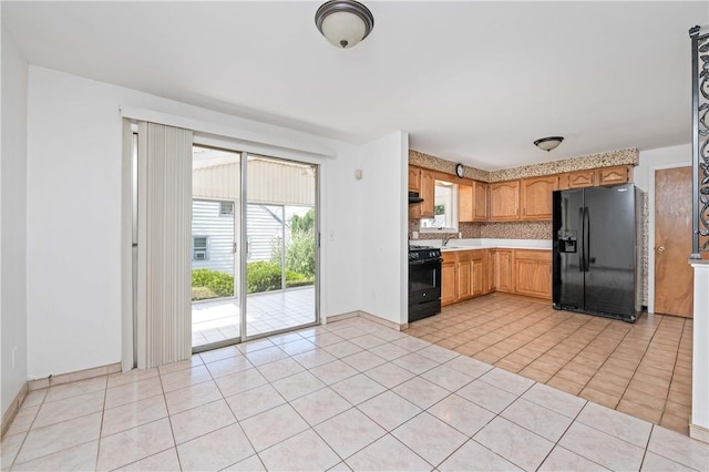 24 Gray St, Rochester, NY 14609 - kitchen with black appliances, light countertops, exhaust hood, light tile patterned floors, and backsplash