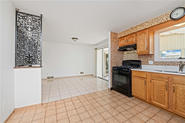 24 Gray St, Rochester, NY 14609 - kitchen featuring black range with gas stovetop, under cabinet range hood, light countertops, backsplash, and light tile patterned flooring