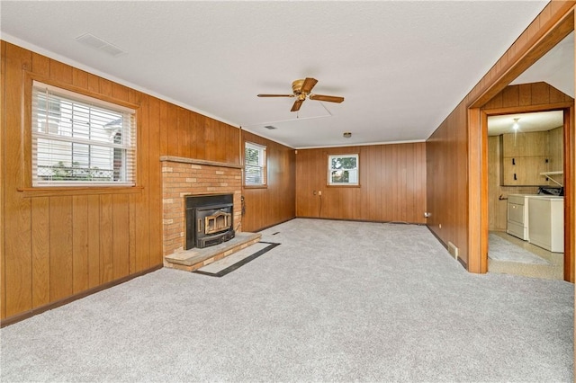 24 Gray St, Rochester, NY 14609 - unfurnished living room with washing machine and clothes dryer, ceiling fan, a wood stove, wooden walls, and carpet flooring