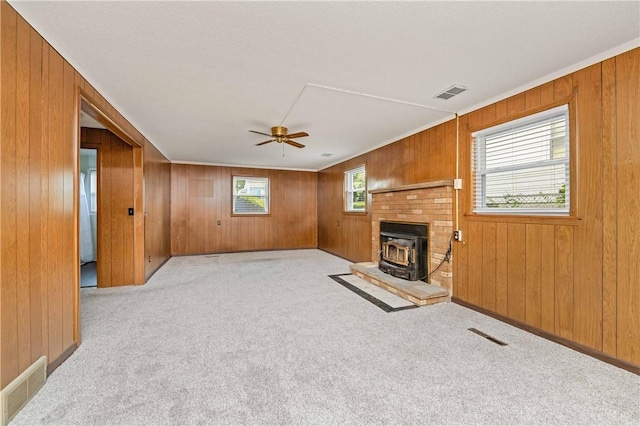 24 Gray St, Rochester, NY 14609 - unfurnished living room featuring a wood stove, wooden walls, carpet flooring, and a ceiling fan