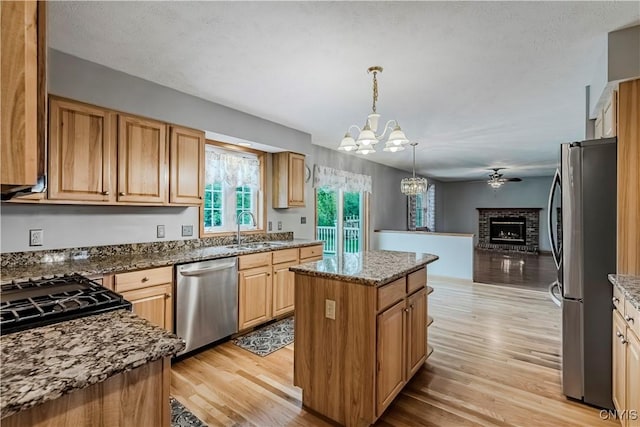 121 Ben Bar Cir, Whitestown, NY 13492 - kitchen with appliances with stainless steel finishes, a chandelier, a brick fireplace, and light wood-style floors