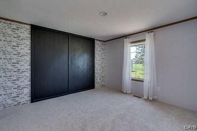 27634 County Route 342, Le Ray, NY 13612 - unfurnished bedroom with light carpet and brick wall