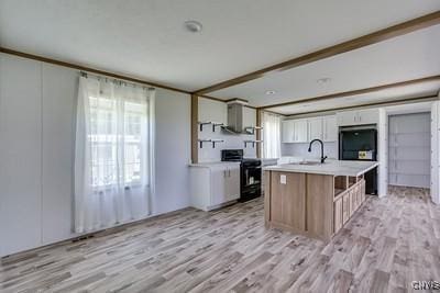 27634 County Route 342, Le Ray, NY 13612 - kitchen featuring range, light countertops, light wood-type flooring, and a center island with sink