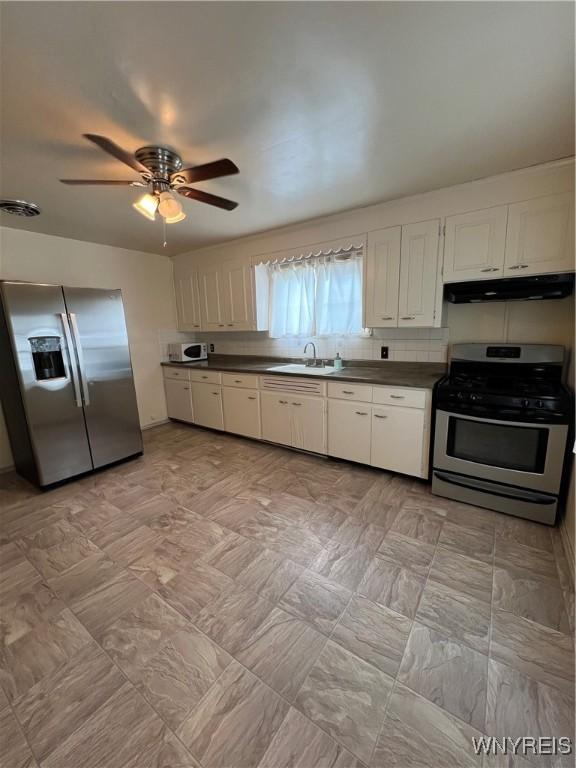 2479 Forest Ave, Niagara Falls, NY 14301 - kitchen featuring appliances with stainless steel finishes, under cabinet range hood, dark countertops, white cabinetry, and ceiling fan