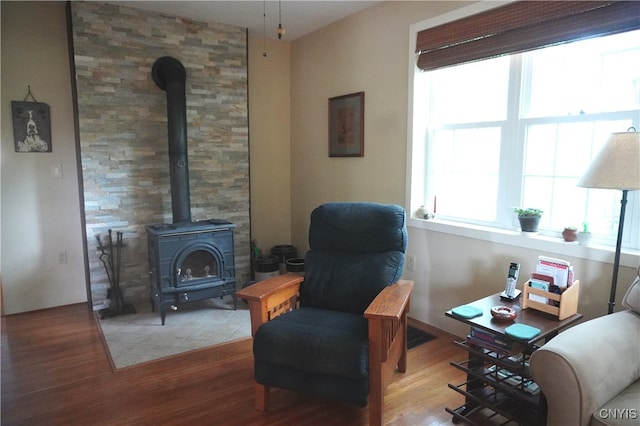 64 Bunner St, Oswego, NY 13126 - sitting room featuring a wood stove, wood finished floors, and healthy amount of natural light