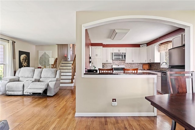 5 Tudor Dr, Owego, NY 13760 - kitchen featuring stainless steel appliances, dark countertops, white cabinetry, light wood-style flooring, and decorative backsplash