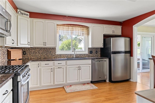 5 Tudor Dr, Owego, NY 13760 - kitchen with stainless steel appliances, arched walkways, white cabinets, decorative backsplash, and light wood finished floors