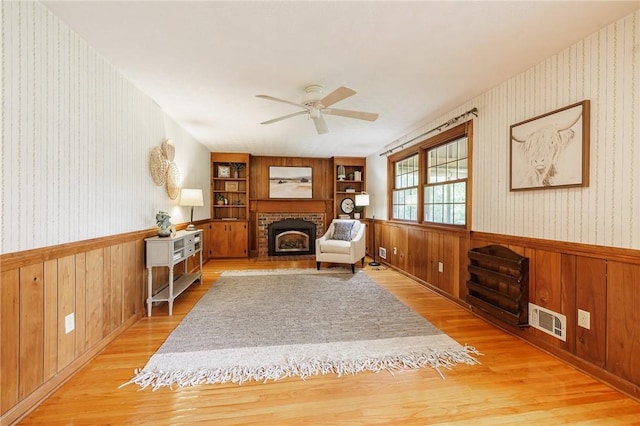 326 Cheese Factory Rd, Mendon, NY 14472 - sitting room with wainscoting, light wood finished floors, wooden walls, ceiling fan, and wallpapered walls
