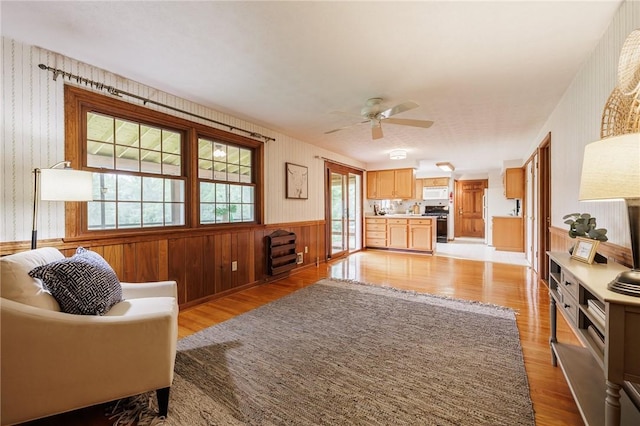 326 Cheese Factory Rd, Mendon, NY 14472 - living area featuring a wainscoted wall, light wood finished floors, ceiling fan, wooden walls, and wallpapered walls