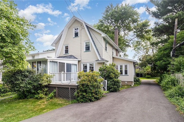 23 Hathaway Rd, Irondequoit, NY 14617 - view of front of home featuring a chimney, a sunroom, and a wooden deck