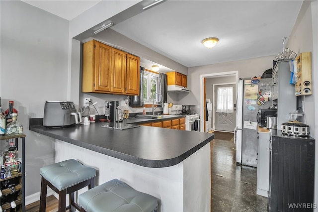 3029 Stieg Rd, Wheatfield, NY 14120 - kitchen featuring white range with gas stovetop, under cabinet range hood, a peninsula, dark countertops, and a kitchen bar