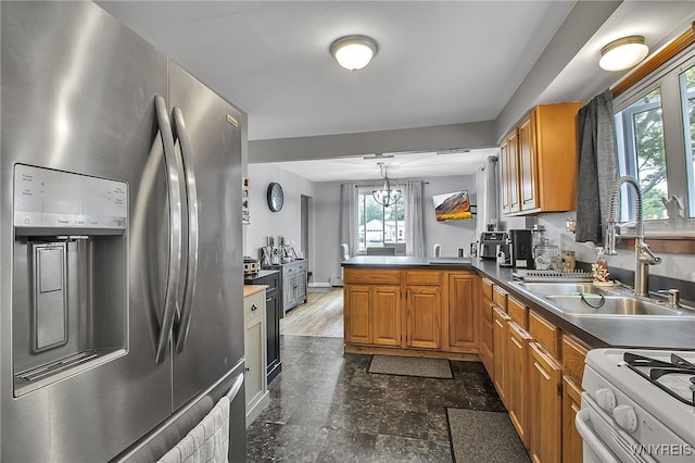 3029 Stieg Rd, Wheatfield, NY 14120 - kitchen featuring stainless steel fridge, white gas range oven, a peninsula, brown cabinets, and hanging light fixtures