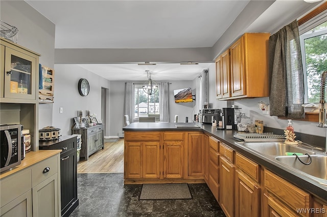 3029 Stieg Rd, Wheatfield, NY 14120 - kitchen with stainless steel microwave, a peninsula, brown cabinetry, and hanging light fixtures