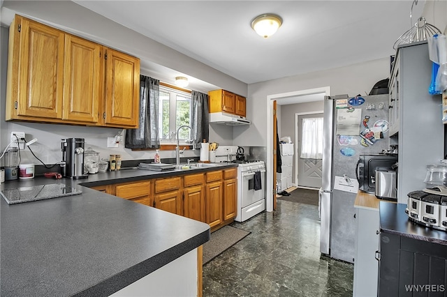 3029 Stieg Rd, Wheatfield, NY 14120 - kitchen with white range with gas cooktop, under cabinet range hood, dark countertops, freestanding refrigerator, and brown cabinetry