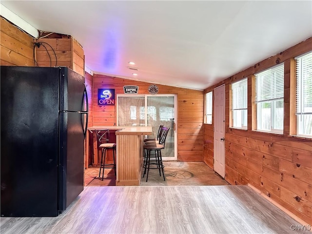 9 Curtis Ave, Lysander, NY 13027 - kitchen with freestanding refrigerator, vaulted ceiling, light wood finished floors, wood walls, and a kitchen breakfast bar