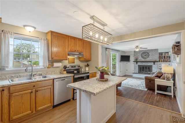22 Tree Line Dr, Clay, NY 13090 - kitchen with stainless steel appliances, under cabinet range hood, light countertops, light wood-style floors, and a fireplace