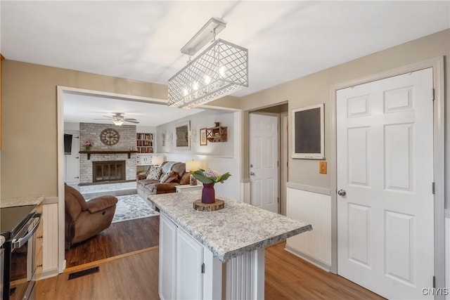 22 Tree Line Dr, Clay, NY 13090 - kitchen featuring electric range, light countertops, a fireplace, a ceiling fan, and wood finished floors