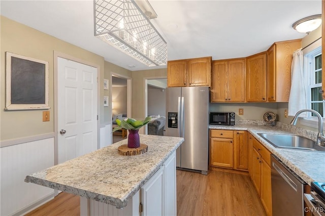 22 Tree Line Dr, Clay, NY 13090 - kitchen featuring appliances with stainless steel finishes, light wood-style floors, a center island, brown cabinetry, and wainscoting