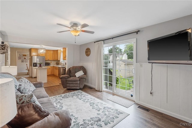 22 Tree Line Dr, Clay, NY 13090 - living area featuring a ceiling fan, light wood finished floors, a wainscoted wall, and a decorative wall