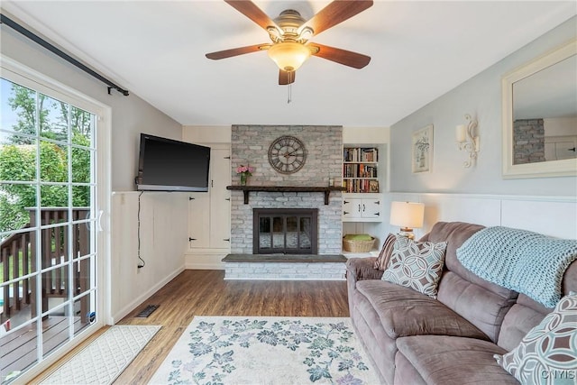 22 Tree Line Dr, Clay, NY 13090 - living room featuring wood finished floors, a ceiling fan, a brick fireplace, and a wainscoted wall