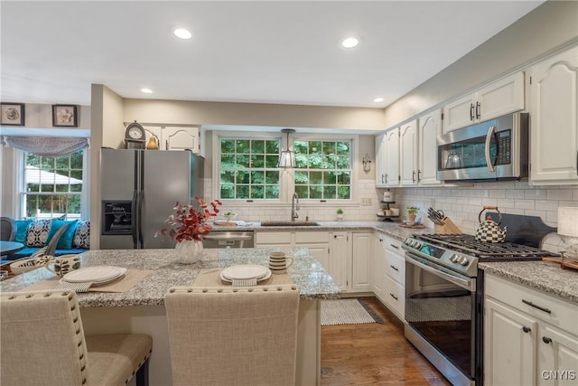 9607 Dunderry, Lysander, NY 13027 - kitchen with appliances with stainless steel finishes, light stone counters, dark wood-type flooring, tasteful backsplash, and recessed lighting