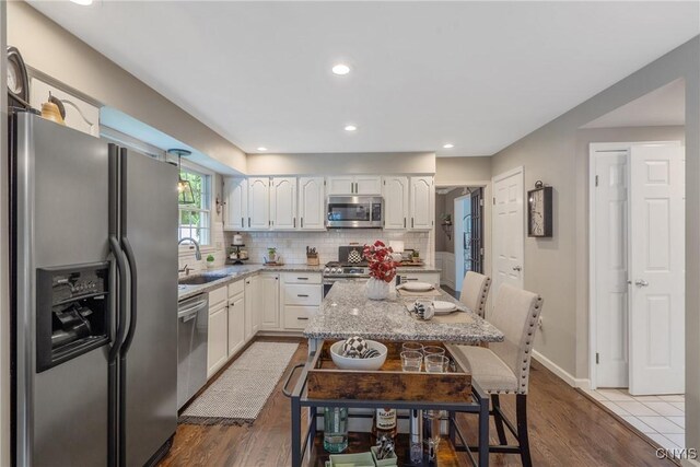 9607 Dunderry, Lysander, NY 13027 - kitchen featuring stainless steel appliances, light stone countertops, tasteful backsplash, a breakfast bar, and white cabinets